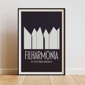 A navy blue framed poster with a minimalist design of abstract building shapes and the text "FILHARMONIA IM. MIECZYSŁAWA KARŁOWICZA" in white letters is displayed against a plain white wall with light wooden flooring.